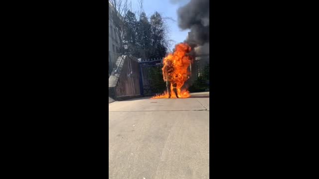 Military man dousing himself in a clear liquid and setting himself on fire